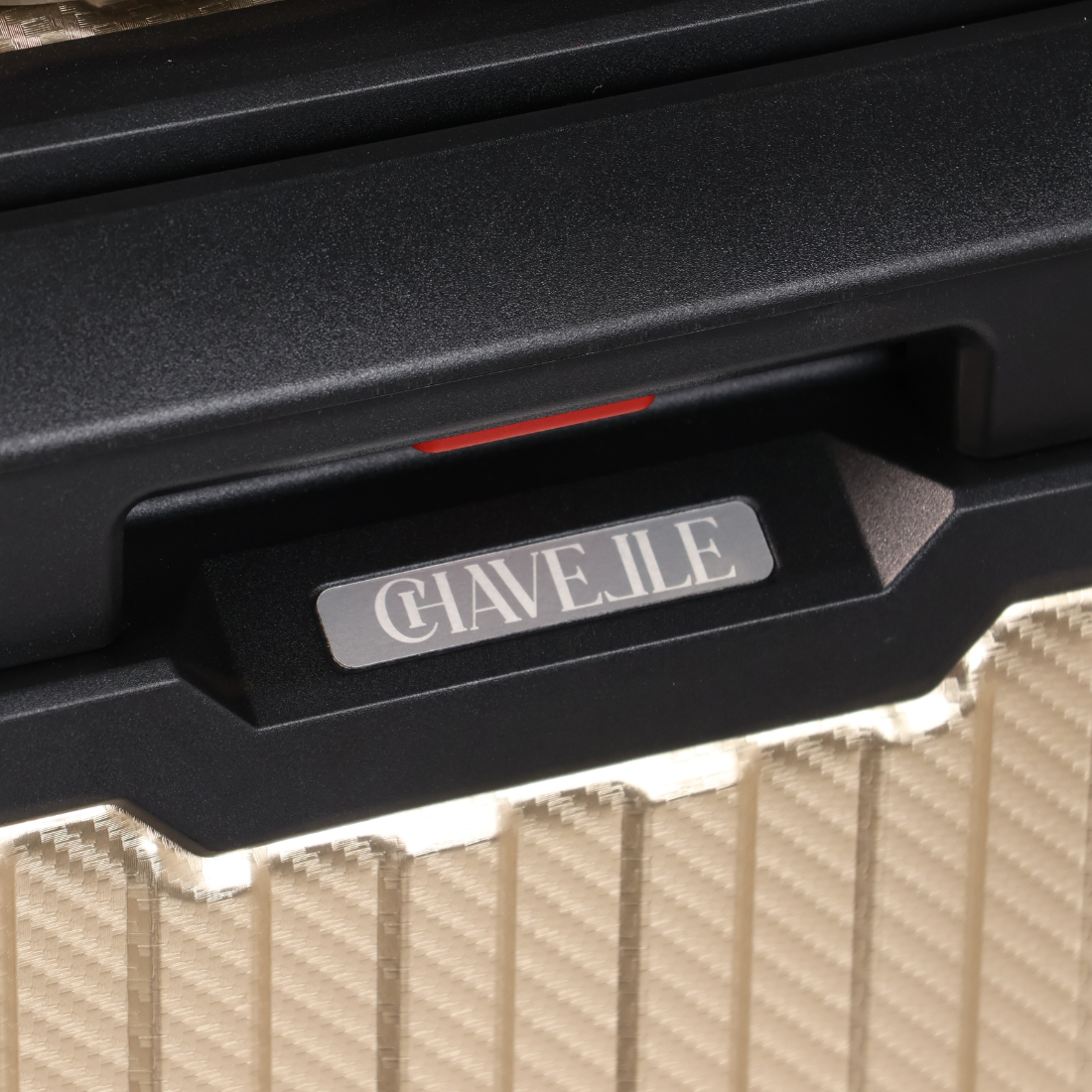 Close-up of a black suitcase handle with 'CHAVELLE' branding on a textured surface.