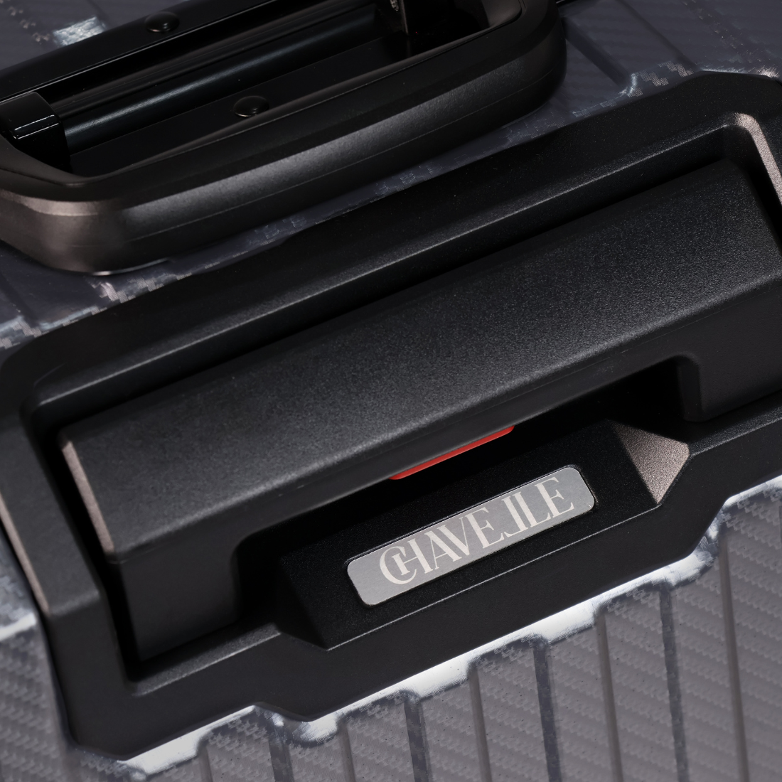 Close-up of a black suitcase handle with 'CHAVELLE' branding on a textured surface.