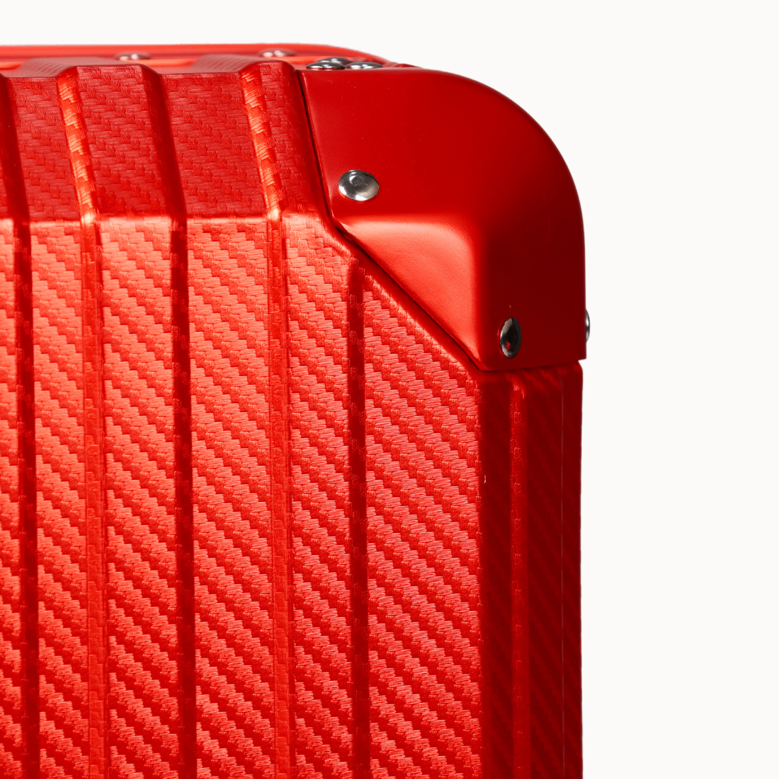 Close-up of a red textured suitcase corner on a white background