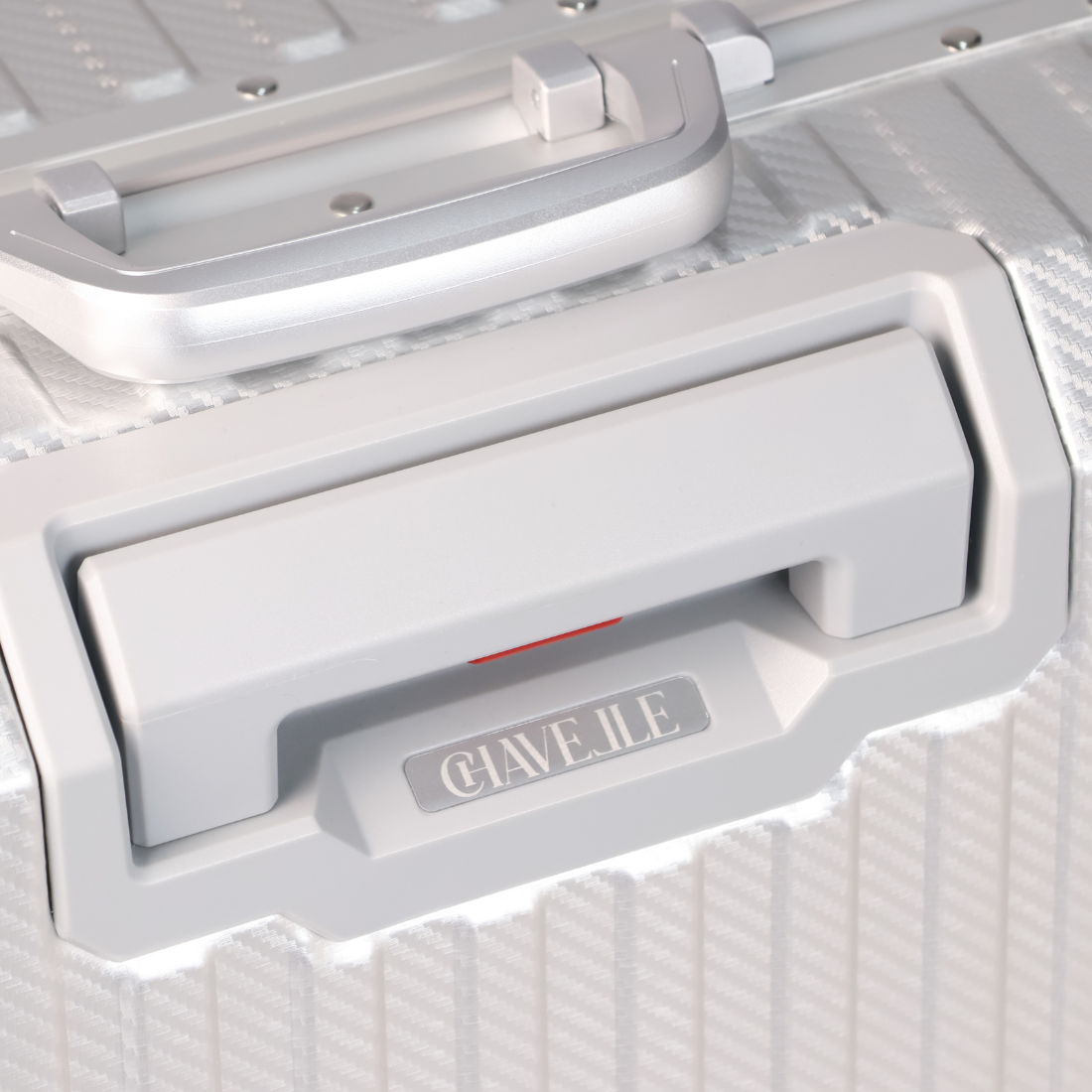 Close-up of a silver suitcase with 'CHAVELLE' branding on a white background