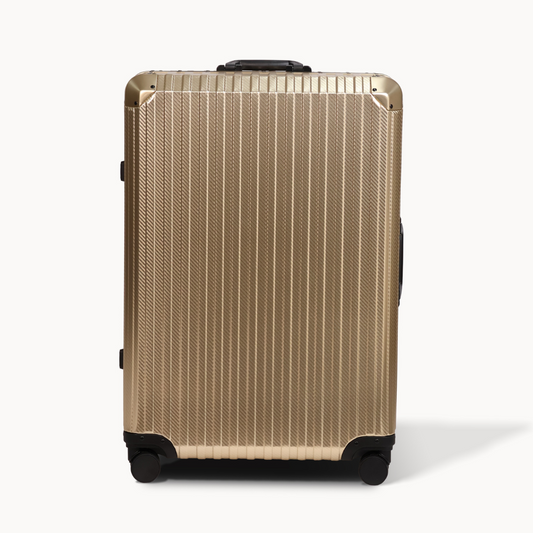 Gold suitcase with black wheels on a white background