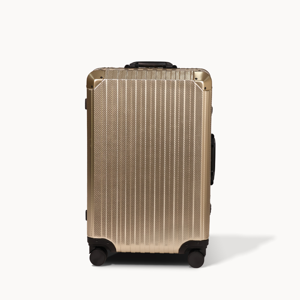 Gold suitcase with black wheels on a white background