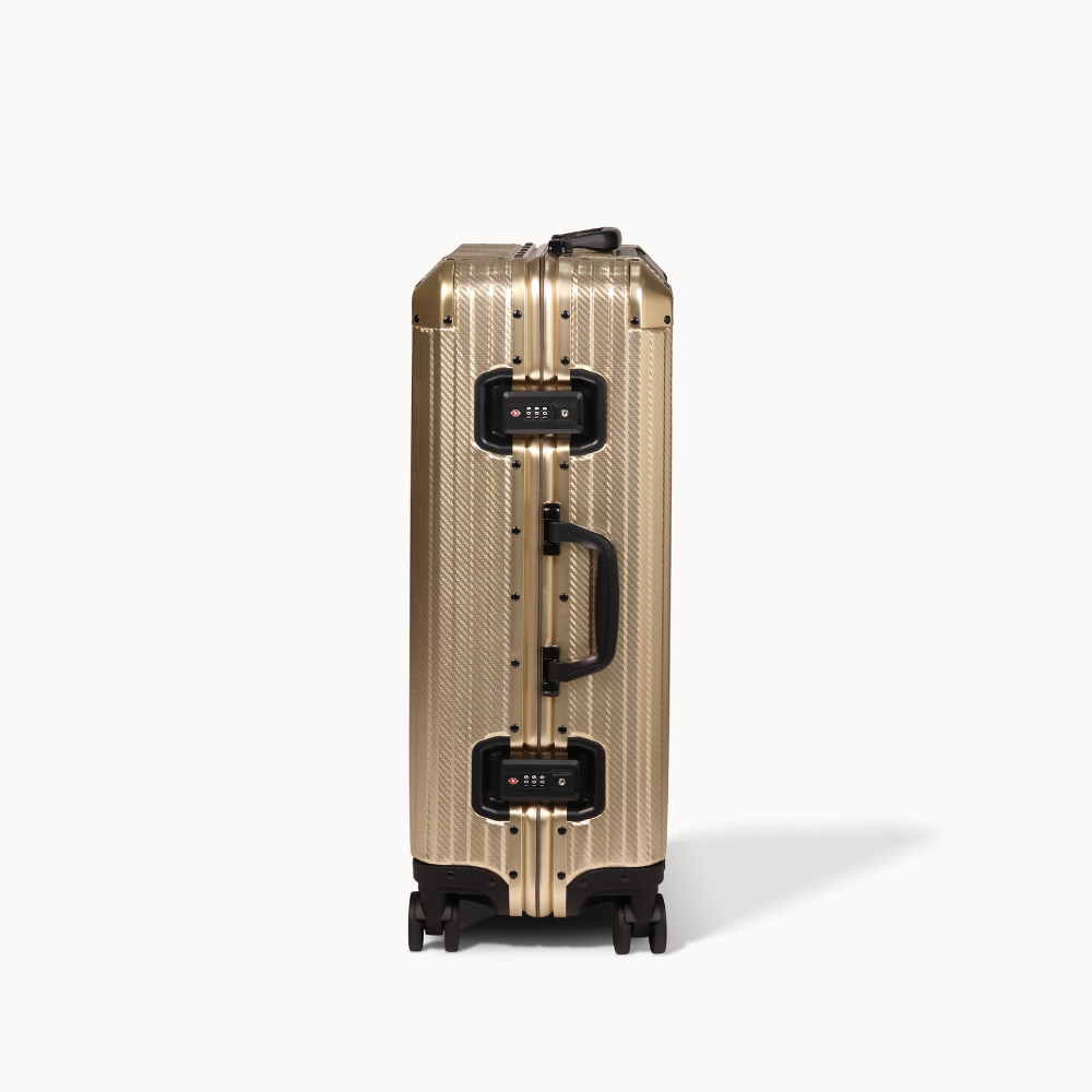 Gold suitcase with black handle and wheels on a white background