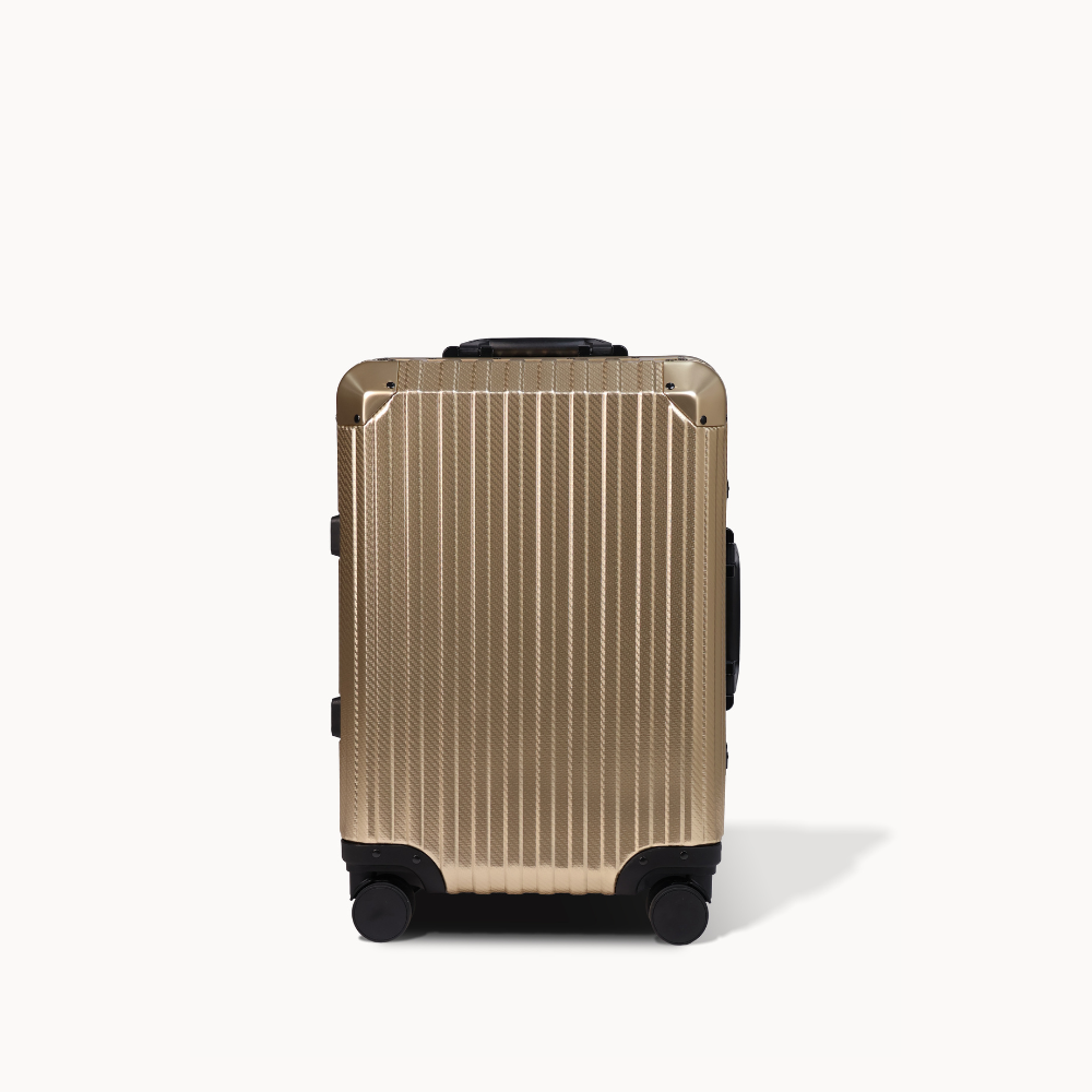 Gold suitcase with black wheels on a white background