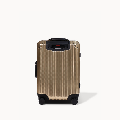 Gold suitcase with black wheels on a white background