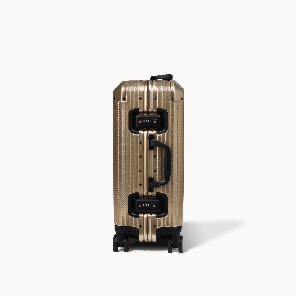 Gold suitcase with black handle and wheels on a white background