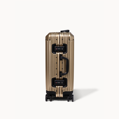 Gold suitcase with black handle and wheels on a white background